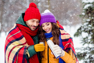 Fototapeta premium Photo of funny pretty girlfriend boyfriend dressed vests covering plaid duvet drinking hot tea walking snow outdoors forest
