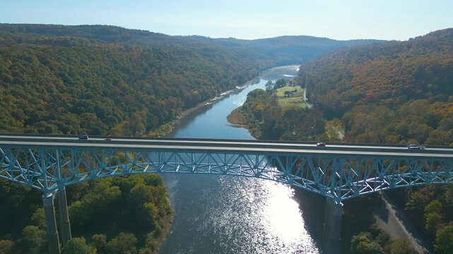 Aerial view of a highway bridge spanning across a river valley with beautiful Fall foliage, drone 4K