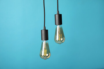 Light bulbs hanging on cords against light blue background