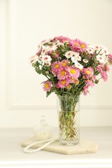 Beautiful flowers in glass vase and decor on white wooden table at home