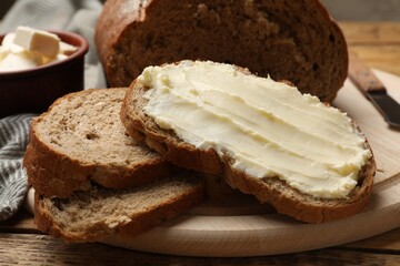 Fresh bread with butter on wooden table, closeup