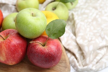 Different whole ripe apples on wooden table, closeup