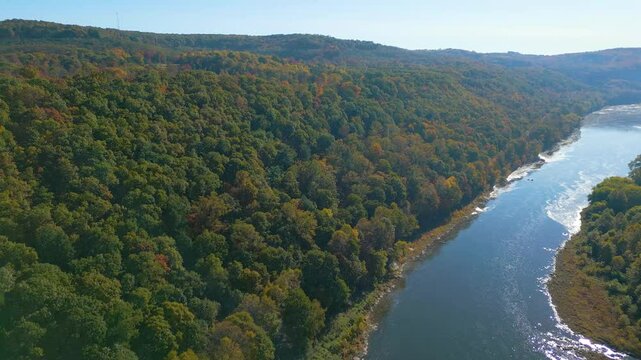 Aerial view of a colorful Autumn forest on the mountainside with a river, drone 4K