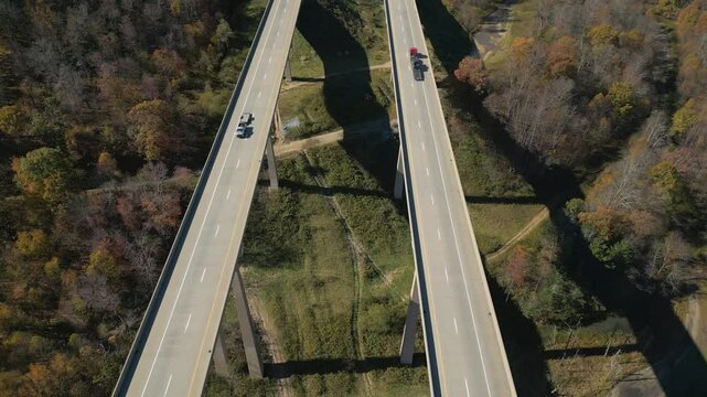Aerial view of parallel highway bridge over a valley with gorgeous Fall foliage, drone 4K