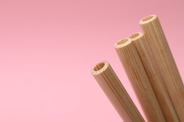 Bamboo drinking straws on pink background, closeup. Space for text