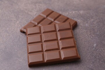 Pieces of delicious milk chocolate on brown table, closeup