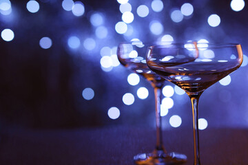 Champagne in glasses on table against blurred lights, closeup. Space for text