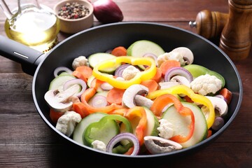 Frying pan with mix of vegetables and mushrooms on wooden table, closeup