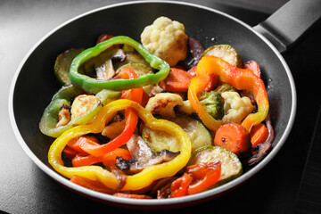 Frying pan with vegetables and mushrooms on stove, closeup