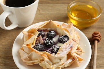 Tasty puff pastry with blueberries, honey and coffee on wooden table, closeup