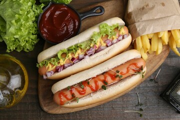 Tasty hot dogs served on wooden table, flat lay
