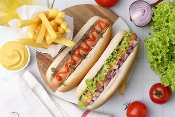 Tasty hot dogs served on white tiled table, flat lay