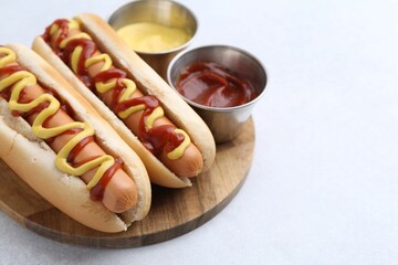 Tasty hot dogs with ketchup and mustard on light table, closeup