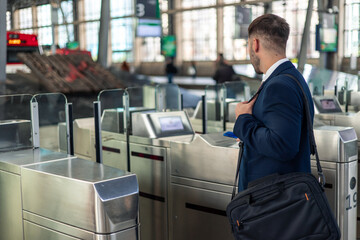 Businessman with briefcase uses contactless payment on train station turnstiles for his commute