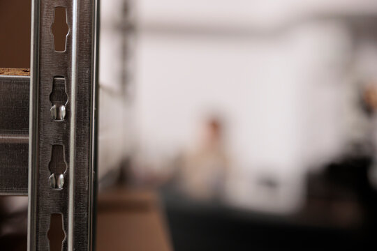 Selective focus of storehouse shelves full with boxes, in background employee working at counter desk, checking clients online orders. Warehouse manager preparing packages for delivery