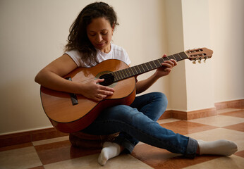 Woman playing acoustic guitar in cozy indoor setting