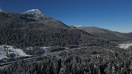 Road on Douglas Island in Juneau Alaska area after first snowfall with mountains and forest of evergreen trees