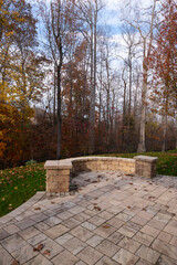 A serene backyard featuring a curved stone patio surrounded by vibrant autumn foliage, creating a peaceful outdoor space ideal for relaxation and nature appreciation.