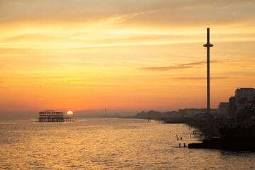Obraz premium A beautiful sunset over the sea with a coastline and a tall, slender tower.