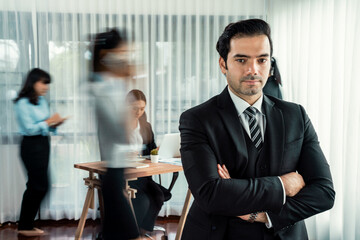 Portrait of happy businessman looking at camera with motion blur background of business people movement in dynamic business meeting. Habiliment