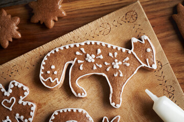 Decorating animal shaped homemade gingerbread Christmas cookie with white icing