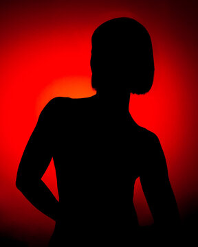 Retrato a contraluz resaltando la figura del sujeto en el cual se ve la silueta y forma con un fondo rojo anaranjado.