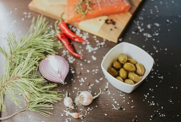 Fresh red salmon on a wooden tray with pepper, salt, garlic, red onion, red pepper, olives with jam