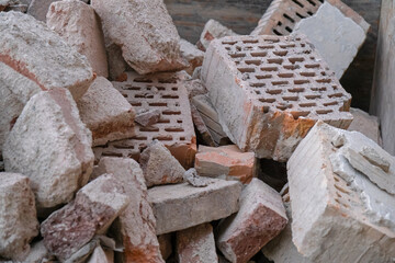 Broken clay ceramic bricks from a ruined wall lie scattered on a construction site, representing...
