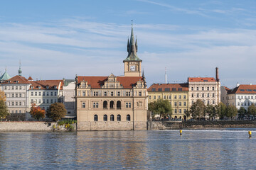 Fototapeta premium Autumn cityscape of Prague with a view of the Old Town. Gothic-style historic buildings are reflected in the Vltava River's calm waters.