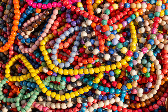  pile of colorful wooden beads used for making traditional necklaces is shown up close, illustrating vibrant and cultural jewelry materials