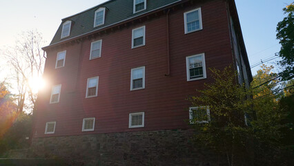Historic brick building on a riverfront during sunset with Fall foliage
