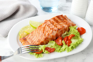 Delicious grilled salmon fillet served on white marble table, closeup