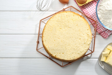 Delicious cut sponge cake and ingredients on white wooden table, flat lay. Space for text