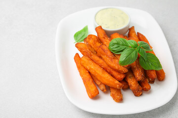 Sweet potato fries, basil and sauce on light grey table, closeup