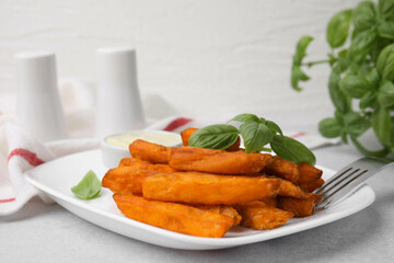 Sweet potato fries, basil and sauce on light grey table, closeup
