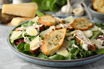 Tasty Caesar salad with chicken on gray textured table, closeup