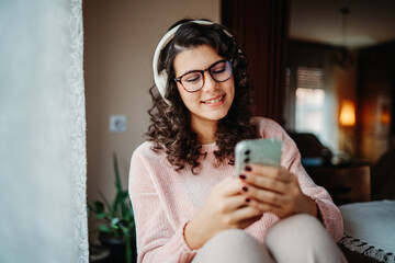 Young caucasian woman enjoying music on wireless headphones at home	