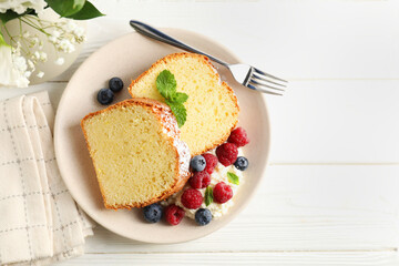 Freshly baked sponge cake, whipped cream, berries and mint on white wooden table, top view. Space for text
