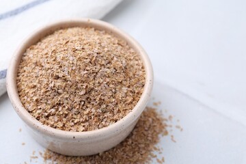 Buckwheat bran in bowl on white table, closeup. Space for text