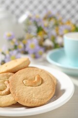 Plate with tasty cashew cookies on white wooden table, closeup. Space for text