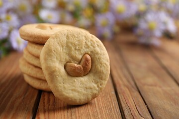 Tasty cashew cookies on wooden table, closeup. Space for text