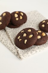 Tasty chocolate cookies with hazelnuts on white table, closeup