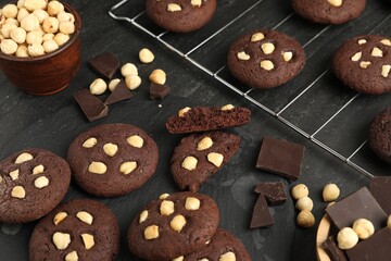 Tasty chocolate cookies with hazelnuts on black table, closeup