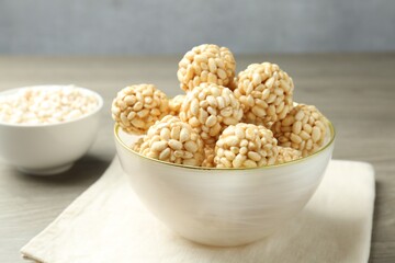 Tasty puffed rice balls in bowl on table, closeup
