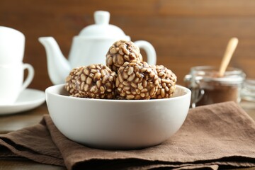 Tasty chocolate puffed rice balls in bowl on table, closeup