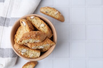 Tasty almond biscuits (Cantuccini) on white tiled table, flat lay. Space for text