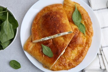 Tasty calzones with cheese and basil on light grey table, top view