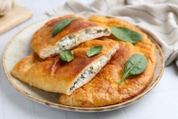 Tasty calzones with basil and cheese on white table, closeup