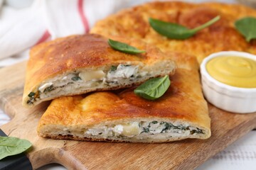 Pieces of tasty calzone with basil, cheese and sauce on table, closeup