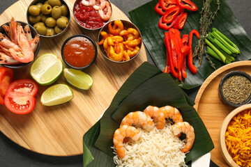 Cut banana leaves with different food, spices and sauce on dark table, flat lay. Healthy eco serving